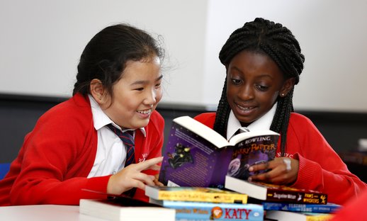 Two young girls happily reading books for pleasure