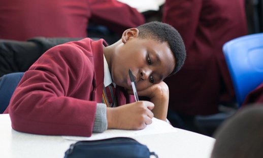 Boy writing in classroom