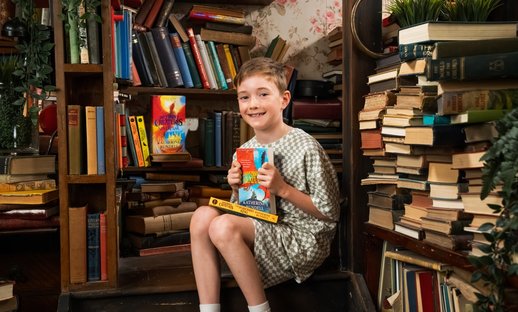 Boy holds copy of book Impossible Creatures - Photo by Will Carne Studios