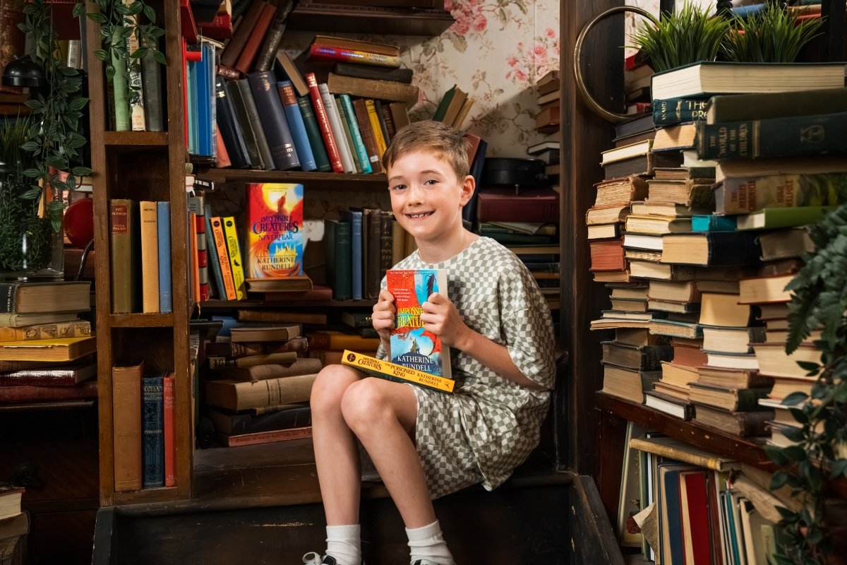 Boy holds copy of book Impossible Creatures - Photo by Will Carne Studios