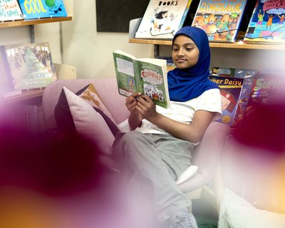 Pupil reads a book on their own in a primary school library