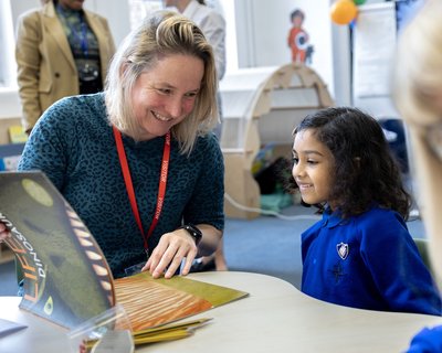 Teacher and pupil enjoy a picture book together in the classroom