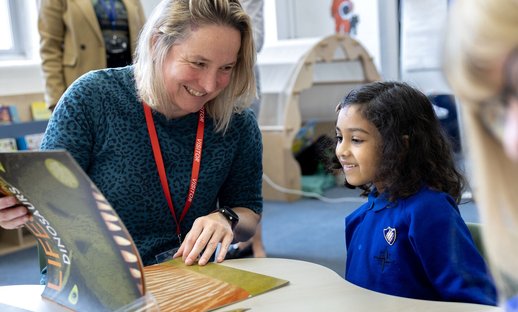Teacher and pupil enjoy a picture book together in the classroom