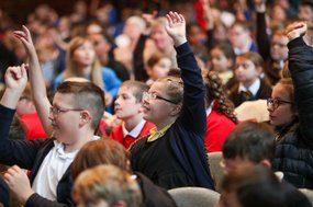 Children with their hands up in an a big assembly event