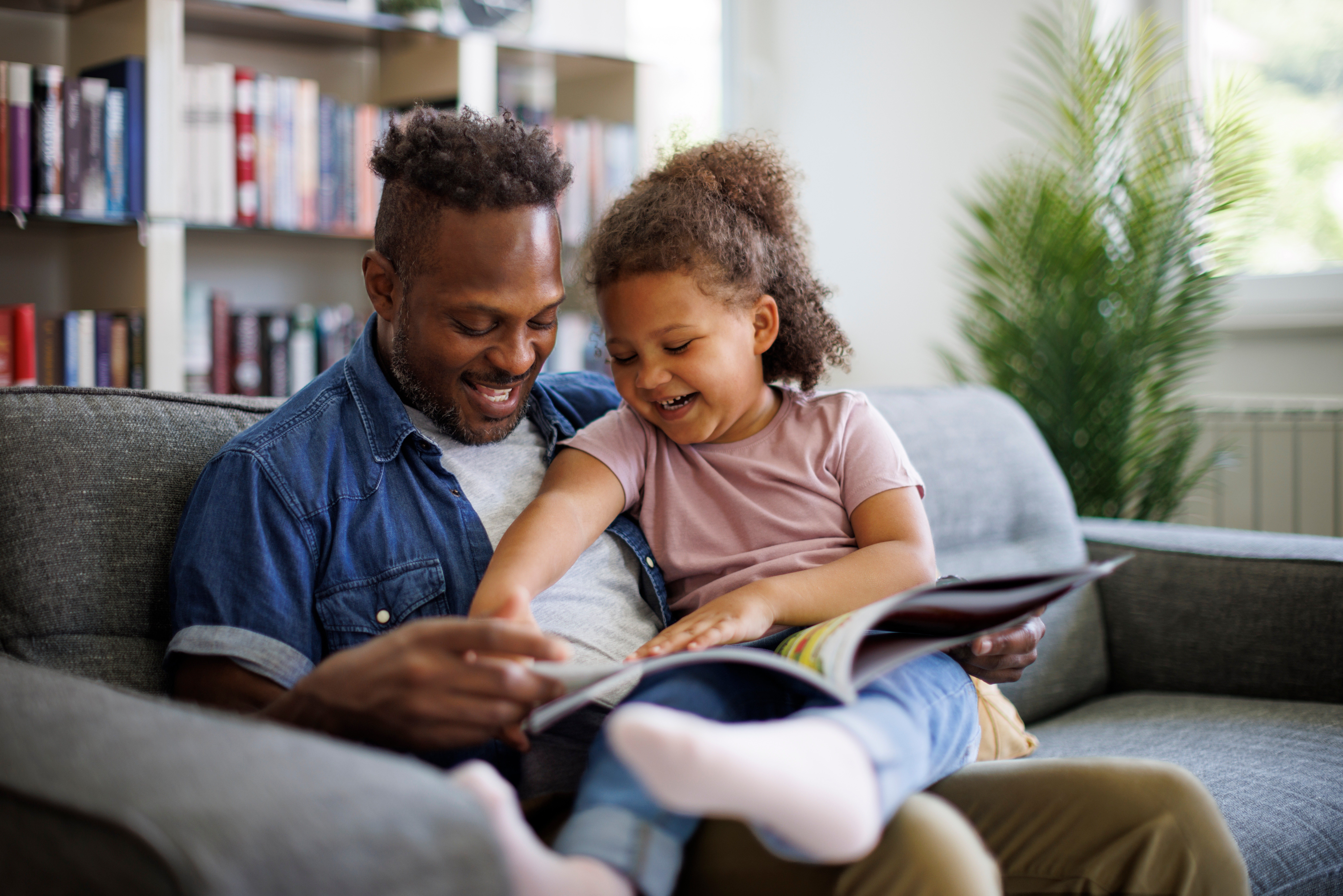 An image of a child looking and laughing at books with her dad