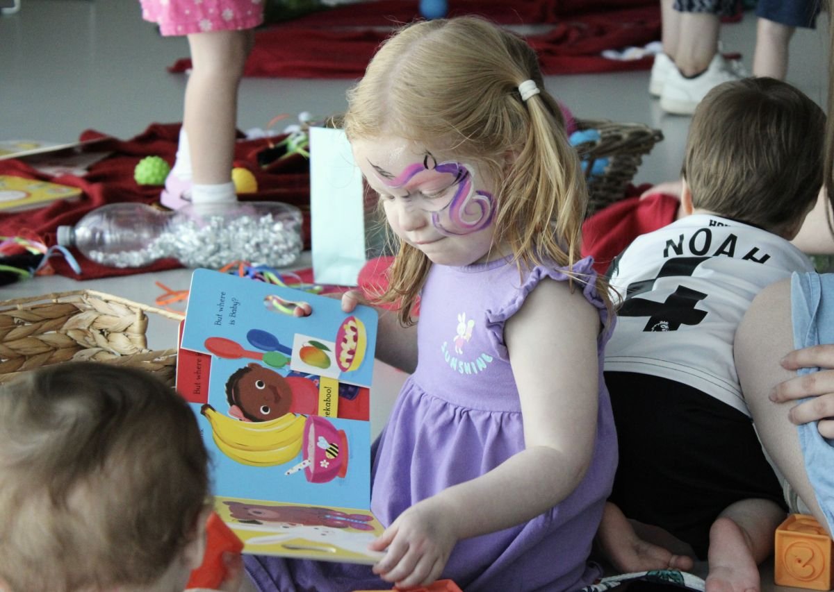 Girl reads a book surrounded by multi-sensory activities at our United by Stories event in Newcastle
