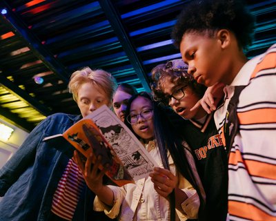 A group of young people look at comic book together.
