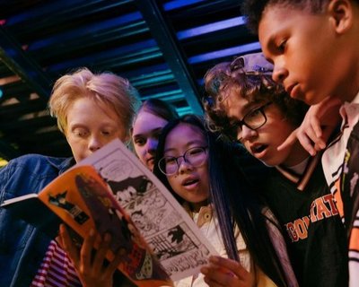 Teens and children look at a comic book (cropped image)