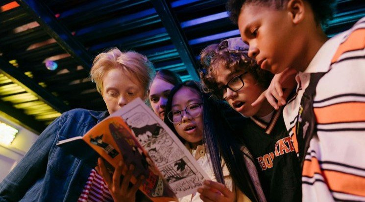 Teens and children look at a comic book (cropped image)