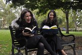 Two women enjoying reading on a park bench