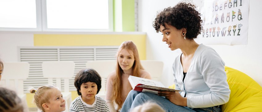 A woman reads aloud to a group of children